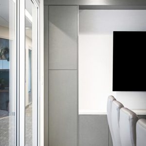 Modern office interior with gray cabinets, a wall-mounted black screen, glass walls, and white chairs lined up beside a table on a gray carpeted floor. Contemporary and minimalistic design.